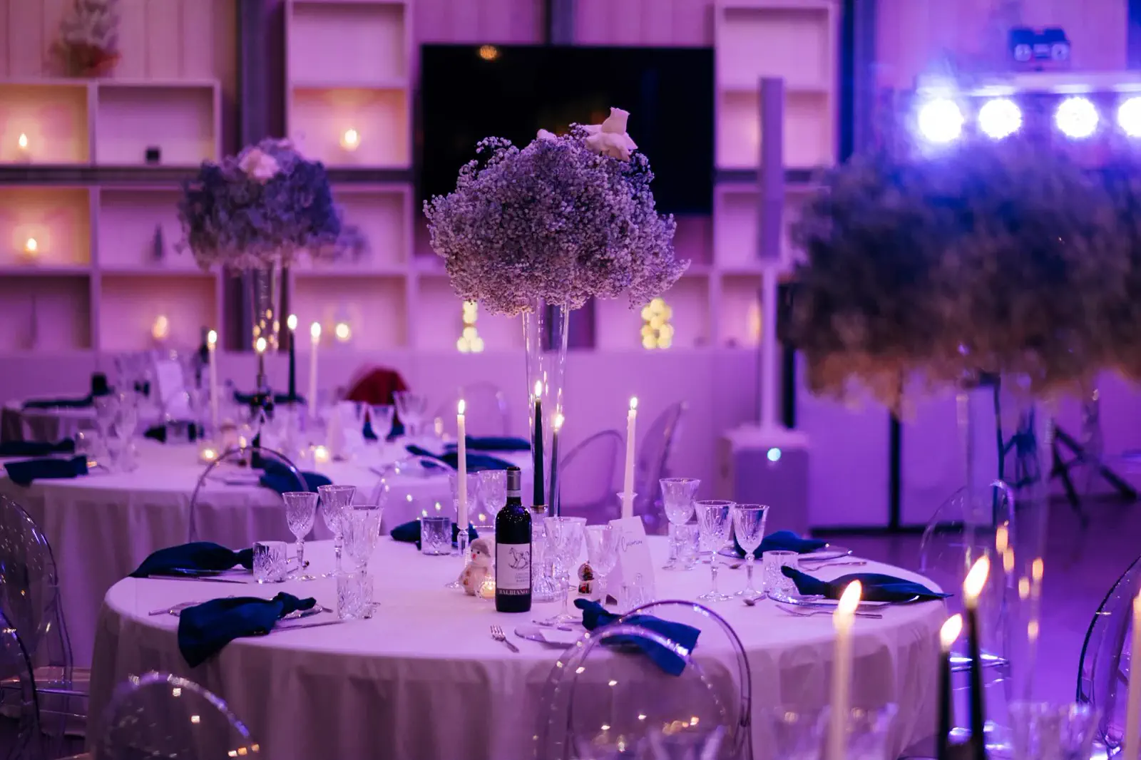 Sala vetrata allestita con tavoli rotondi, centrotavola e luci scenografiche per una festa