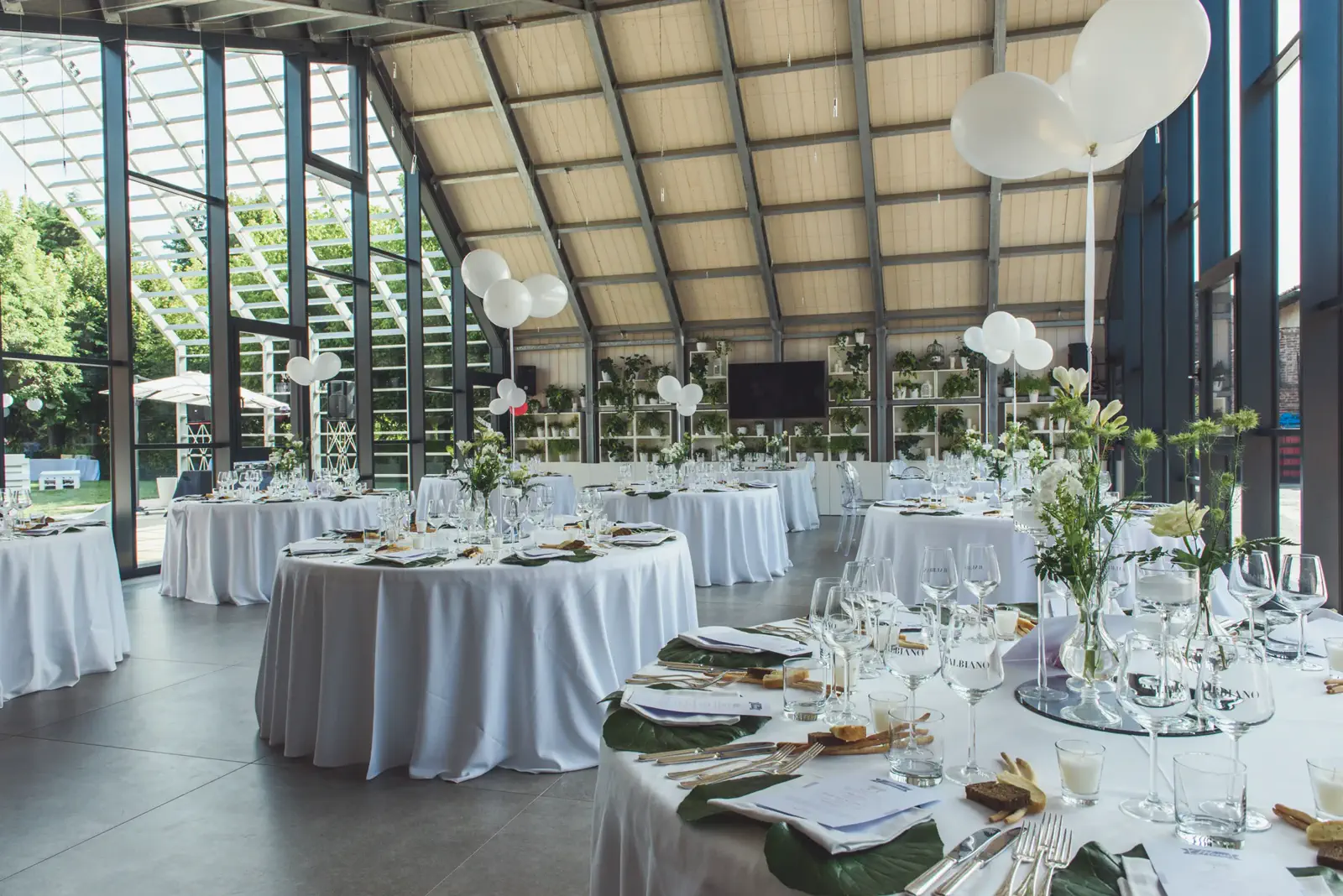 Sala vetrata allestita con tavoli rotondi e affaccio sul giardino